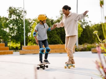 Skateboard für Anfänger: Junge wird von Trainerin im Skateboarding unterrichtet. Skateboard für Anfänger: Junge wird von Trainerin im Skateboarding unterrichtet.