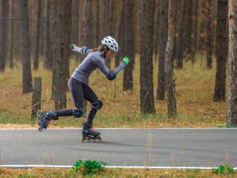 Inline-Speedskating: Eine Frau fährt auf Inlinern und Schutzausrüstung eine Strasse entlang.