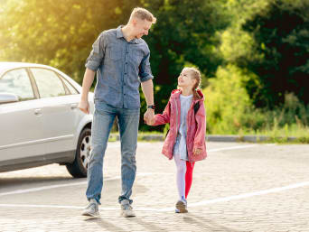 Kinder mit dem Auto zur Schule bringen – Vater parkt in einer Nebenstraße und läuft mit seiner Tochter zur Schule. Kinder mit dem Auto zur Schule bringen – Vater parkt in einer Nebenstraße und läuft mit seiner Tochter zur Schule.