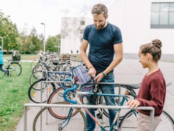 Schulweg mit Fahrrad: Vater begleitet Tochter mit dem Fahrrad zur Schule. Schulweg mit Fahrrad: Vater begleitet Tochter mit dem Fahrrad zur Schule.