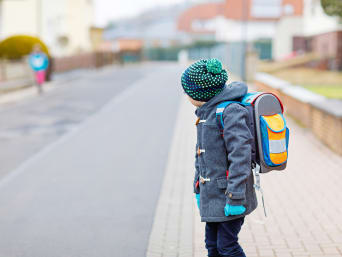 Verkehrserziehung für Kinder: Kleiner Junge steht auf dem Gehsteig und schaut auf die Straße. Verkehrserziehung für Kinder: Kleiner Junge steht auf dem Gehsteig und schaut auf die Straße.