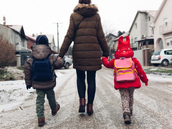 Lopend naar school – Moeder loopt met de kinderen naar school.