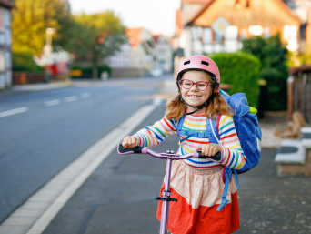 Roller fahren für Kinder: Mädchen mit Tretroller auf dem Weg zur Schule. Roller fahren für Kinder: Mädchen mit Tretroller auf dem Weg zur Schule.