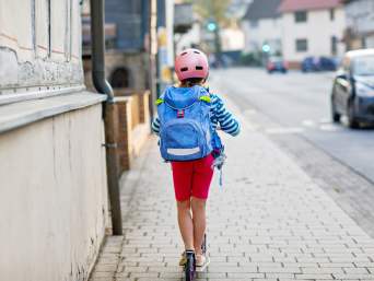Roller fahren Kinder: Mädchen fährt mit dem Roller zur Schule. Roller fahren Kinder: Mädchen fährt mit dem Roller zur Schule.