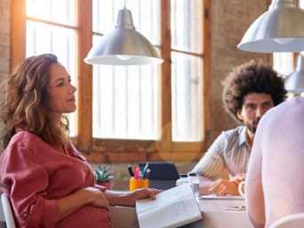 Arbeiten Schwangerschaft: Schwangere Frau nimmt an einer Besprechung im Team teil. Arbeiten Schwangerschaft: Schwangere Frau nimmt an einer Besprechung im Team teil.