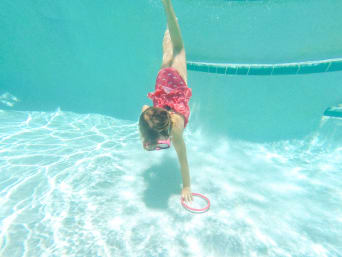 Mädchen taucht in Schwimmbecken nach einem Reifen für die Schwimmabzeichen-Prüfung Mädchen taucht in Schwimmbecken nach einem Reifen für die Schwimmabzeichen-Prüfung