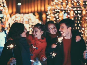 New Year’s Eve with kids: Family lights sparklers together. New Year’s Eve with kids: Family lights sparklers together.