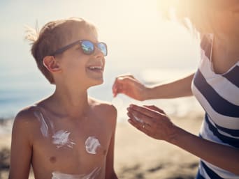 Sonnenschutz für Kinder: Mutter cremt ihren Sohn mit Sonnencreme ein. Sonnenschutz für Kinder: Mutter cremt ihren Sohn mit Sonnencreme ein.