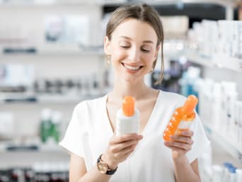 Was tun gegen Sonnenbrand: Frau vergleicht verschiedene After-Sun-Lotionen in der Apotheke. Was tun gegen Sonnenbrand: Frau vergleicht verschiedene After-Sun-Lotionen in der Apotheke.