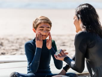 Sonnencreme beim Sport: Mutter und Sohn cremen sich vorm Surfen mit geeigneter Sonnencreme ein. Sonnencreme beim Sport: Mutter und Sohn cremen sich vorm Surfen mit geeigneter Sonnencreme ein.