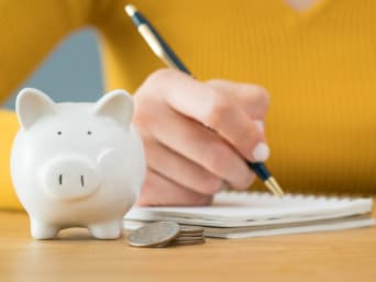 Geld sparen - vrouw houdt haar budget bij in een notitieboekje.