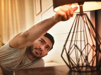 Stroom besparen - jonge man doet een lamp uit. Stroom besparen - jonge man doet een lamp uit.