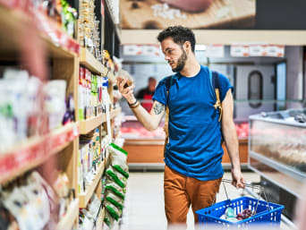 Goedkoop winkelen: Man vergelijkt prijzen in de supermarkt. Goedkoop winkelen: Man vergelijkt prijzen in de supermarkt.