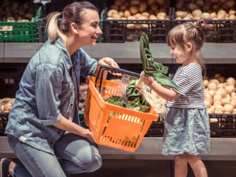 Geld besparen op boodschappen: Moeder en dochter kopen seizoensgroenten. Geld besparen op boodschappen: Moeder en dochter kopen seizoensgroenten.