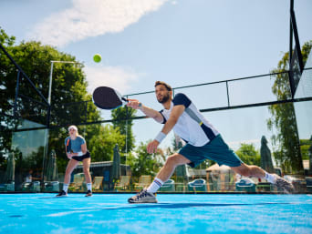Padel Tennis lernen: Ein Padel-Spieler nimmt den Ball mit seinem Schläger an.  Padel Tennis lernen: Ein Padel-Spieler nimmt den Ball mit seinem Schläger an.