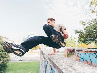 Parkour lernen: Traceur bei einem Vault über eine Mauer.