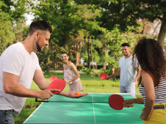 Tischtennis für Anfänger: Eine Gruppe von Freunden spielt Tischtennis im Park. Tischtennis für Anfänger: Eine Gruppe von Freunden spielt Tischtennis im Park.