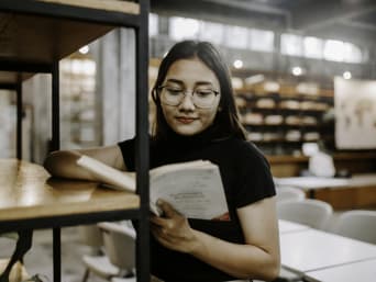 Welches Studium passt zu mir? - Schülerin liest ein Buch zur Studienorientierung in der Bibliothek.