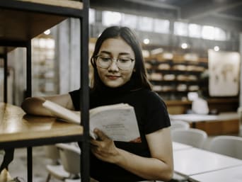 Schülerin liest ein Buch zur Studienorientierung in der Bibliothek. Schülerin liest ein Buch zur Studienorientierung in der Bibliothek.