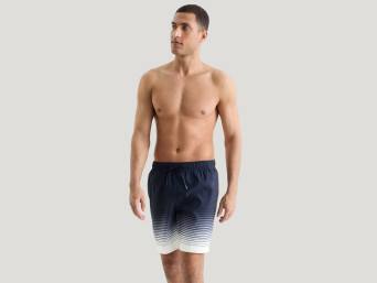 Boardshort homme : homme portant un bermuda de bain jusqu’aux genoux. Boardshort homme : homme portant un bermuda de bain jusqu’aux genoux.