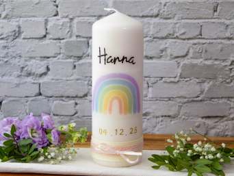 A baptism candle with a rainbow standing on a table.  A baptism candle with a rainbow standing on a table.
