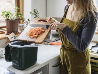 Müll richtig trennen: Frau leert Karottenschalen in den Biomüll. Müll richtig trennen: Frau leert Karottenschalen in den Biomüll.