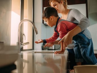Proefjes met water – moeder en zoon gebruiken een waterkraan. Proefjes met water – moeder en zoon gebruiken een waterkraan.