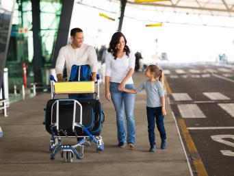 Flugreise mit Kindern: Eltern mit kleiner Tochter und Gepäck-Trolley am Flughafen. Flugreise mit Kindern: Eltern mit kleiner Tochter und Gepäck-Trolley am Flughafen.