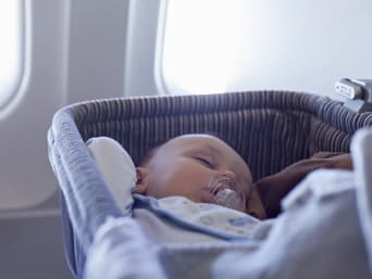 Vliegen met baby: baby slaapt in vliegtuigwieg.