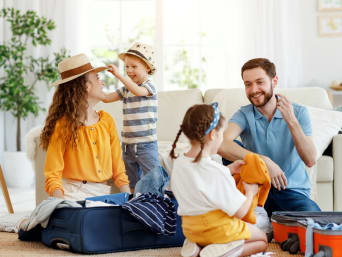 Packliste Urlaub mit Kind – Familie packt zusammen ihre Koffer. Packliste Urlaub mit Kind – Familie packt zusammen ihre Koffer.