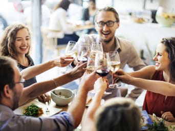 Aargau Spezialitäten: Eine Gruppe von Freunden stösst in einem Restaurant mit einem Glas Wein an.