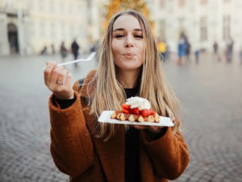Chocolade-festivals en wafel-evenementen: vrouw eet een wafel met aardbeien en slagroom. Chocolade-festivals en wafel-evenementen: vrouw eet een wafel met aardbeien en slagroom.