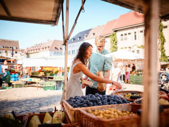Spezialitäten Vorarlberg: Paar kauft Obst an einem Stand auf dem Markt. Spezialitäten Vorarlberg: Paar kauft Obst an einem Stand auf dem Markt.