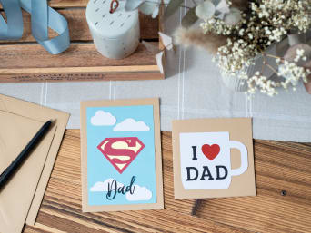 Materials for a Father's Day card with superhero logo.