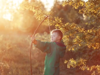 Ideeën voor bosactiviteiten met kinderen: jongen schiet met pijl en boog. Ideeën voor bosactiviteiten met kinderen: jongen schiet met pijl en boog.