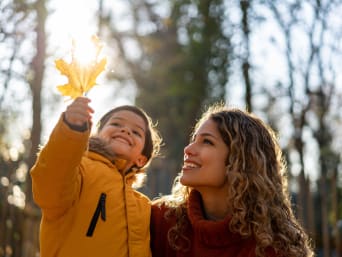 Jahreszeiten im Wald – Mutter und Kind betrachten ein Herbstblatt. 