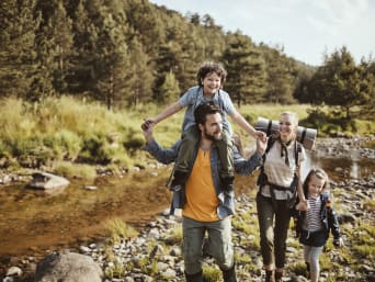 Gezinswandeling plannen: Ouders wandelen met kinderen langs een beekje. Gezinswandeling plannen: Ouders wandelen met kinderen langs een beekje.