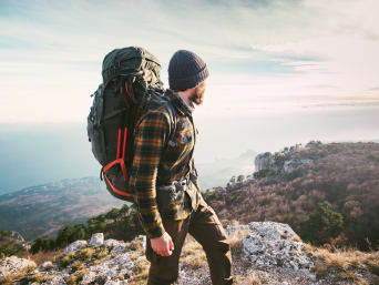 Hiking accessories: a man with a hiking backpack looking into the distance. Hiking accessories: a man with a hiking backpack looking into the distance.