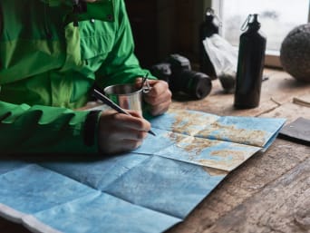 A hiker planning his hiking route with a map. A hiker planning his hiking route with a map.