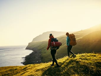 Two hikers with full hiking gear approaching the coast. Two hikers with full hiking gear approaching the coast.