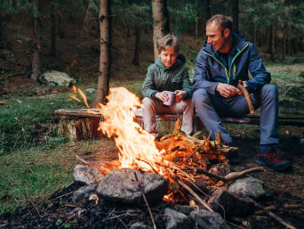 Vater und Sohn machen ein Lagerfeuer an einer Feuerstelle. Vater und Sohn machen ein Lagerfeuer an einer Feuerstelle.