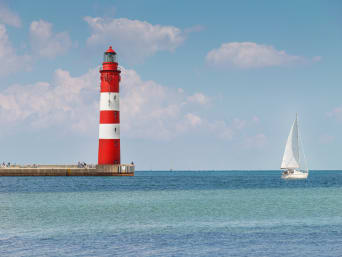 Zeilboot vaart op rustig zeewater in de buurt van een vuurtoren. Zeilboot vaart op rustig zeewater in de buurt van een vuurtoren.