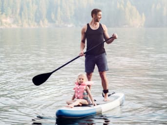 Kinder SUP – Kleines Mädchen fährt mit Schwimmweste auf dem Familienboard mit. Kinder SUP – Kleines Mädchen fährt mit Schwimmweste auf dem Familienboard mit.