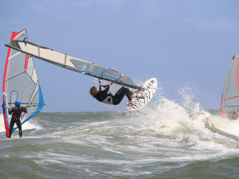 Windsurfen: Ein Windsurfer führt auf seinem Surfboard einen Sprung in die Luft durch. Windsurfen: Ein Windsurfer führt auf seinem Surfboard einen Sprung in die Luft durch.