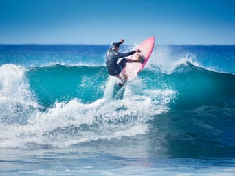 Surfen: Surfer startet mit seinem Surfboard auf eine Welle. Surfen: Surfer startet mit seinem Surfboard auf eine Welle.
