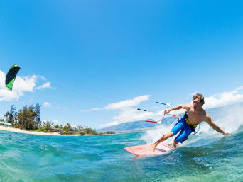 Kitesurfen: Ein junger Kitesurfer surft nahe des Strandes und fährt eine Kurve. Kitesurfen: Ein junger Kitesurfer surft nahe des Strandes und fährt eine Kurve.
