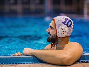 Unterwasserhockey Ausrüstung: Unterwasserhockey-Spieler trägt Wasserballkappe und hält sich am Beckenrand fest. Unterwasserhockey Ausrüstung: Unterwasserhockey-Spieler trägt Wasserballkappe und hält sich am Beckenrand fest.