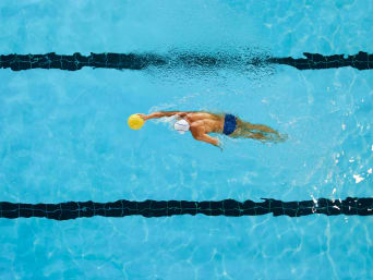 Wasserball Training: Wasserballspieler übt das Schwimmen mit Ball im Becken. Wasserball Training: Wasserballspieler übt das Schwimmen mit Ball im Becken.