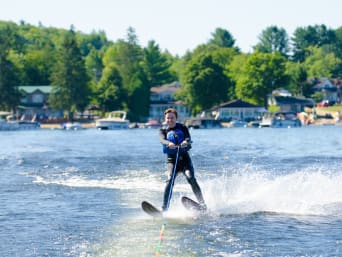 Wasserski fahren: Frau im Neoprenanzug fährt hinter einem Motorboot Wasserski. Wasserski fahren: Frau im Neoprenanzug fährt hinter einem Motorboot Wasserski.