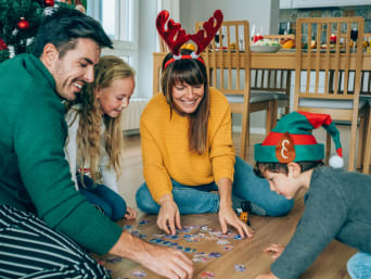 Christmas games for kids: a family sitting together on their living room floor doing a puzzle. Christmas games for kids: a family sitting together on their living room floor doing a puzzle.